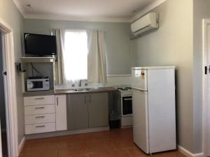 a kitchen with a white refrigerator and a window at Restawile Motel in Busselton