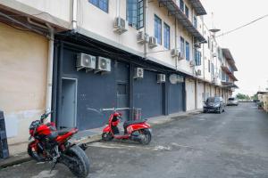 a red scooter parked in front of a building at RedDoorz Plus near Batam City Square in Batam Center