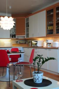 Aliisa's Apartment في روفانييمي: مطبخ مع كراسي حمراء وطاولة مع نبات الفخار