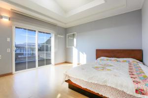 a bedroom with a bed and a large window at Seommaeul Pension in Geoje 