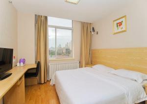 a bedroom with a bed and a desk and a television at JUNYI Hotel Shandong Qingdao Huangdao District Shiyou University in Xianlang