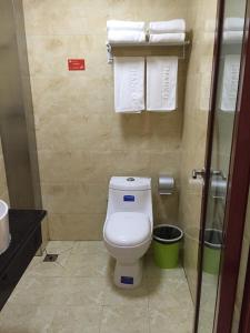 a bathroom with a toilet and towels on the wall at JUNYI Hotel Shandong Zaozhuang Shanting District Xinyuan Road in Zhaozhuang