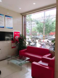 uma sala de estar com um sofá vermelho e uma mesa de vidro em Thank Inn Plus Hotel Jiangsu Taizhou Taixing Jingjiang Primary School em Taixing