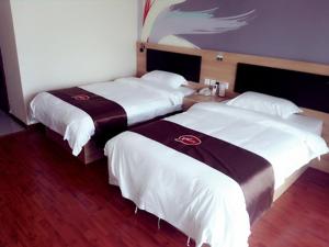 2 Betten in einem Hotelzimmer mit weißer Bettwäsche in der Unterkunft Thank Inn Plus Hotel Jiangsu Gaoxiang District XuZhuang Branch in Taizhou