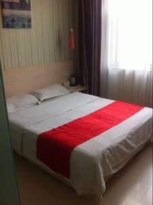 uma cama com um cobertor vermelho e branco em Thank Inn Chain Hotel Fei Town Jianshe Road em Feixian