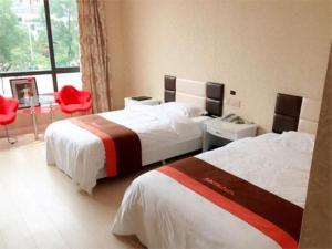 a hotel room with two beds and a red chair at JUNYI Hotel Jiangsu Wuxi Yixing Guibin Avenue in Yixing