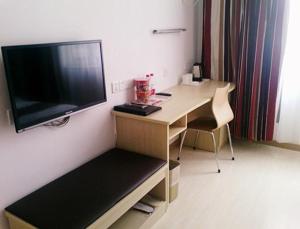 Habitación con escritorio y TV en la pared. en Thank Inn Chain Hotel Hebei Shijiazhuang Yuanshi Changshan Road, en Maoyi