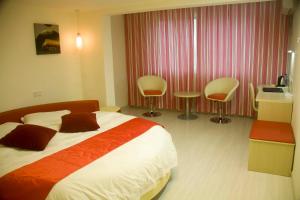 une chambre d'hôtel avec un lit et deux chaises dans l'établissement Thank Inn Chain Hotel Jiangsu Huaian Lianshui Gaogou Town No.1 Street, à Duimatou
