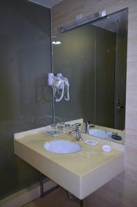 baño con lavabo y espejo grande en JUNYI Hotel Shandong Qingdao Huangdao District Shiyou University en Xianlang
