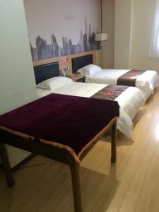 twee bedden in een kamer met een tafel erin bij JUNYI Hotel Jiangsu Nanjing University of Information Science and Technology in Nanjing