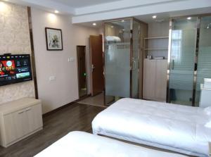 - une chambre avec 2 lits et une télévision dans l'établissement JUNYI Hotel Jiangsu Suzhou Mudu Ancient Town, à Suzhou