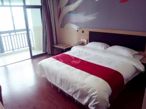 Schlafzimmer mit einem Bett mit einer roten und weißen Decke in der Unterkunft Thank Inn Plus Hotel Jiangsu Gaoxiang District XuZhuang Branch in Taizhou