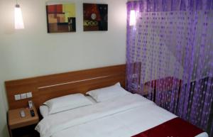 ein Schlafzimmer mit einem Bett mit einem Kopfteil aus Holz in der Unterkunft Thank Inn Chain Hotel Jiangsu Huaian Lianshui Dongding in Paifang
