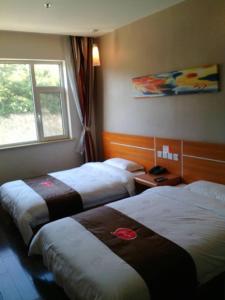 um quarto de hotel com duas camas e uma janela em Thank Inn Chain Hotel Shanxi Lvliang Jiaokou County West Street em Xiazhuang