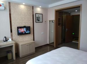 - une chambre avec un lit et une télévision murale dans l'établissement JUNYI Hotel Jiangsu Suzhou Mudu Ancient Town, à Suzhou