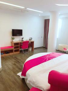 um quarto com uma cama rosa e branca e uma secretária. em Thank Inn Plus Hotel Jiangsu Taizhou Taixing Jingjiang Primary School em Taixing