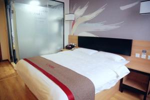 a bedroom with a large white bed and a desk at Thank Inn Chain Hotel Jiangsu Zhenjiang Danyang Train Station in Jinglin