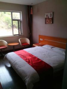 um quarto com uma cama grande e uma janela em Thank Inn Chain Hotel Shanxi Lvliang Jiaokou County West Street em Xiazhuang