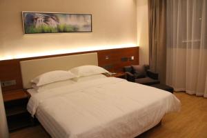 a hotel room with a white bed and a chair at Thank Inn Plus Hotel Fengxian Xidu in Xidu
