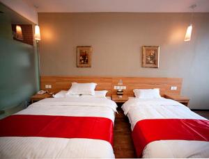 two beds in a hotel room with red and white sheets at Thank Inn Chain Hotel Jiangsu Yangzhou Shaobo Grand Canal in Yangzhou