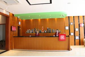 two people are sitting at a counter in a lobby at Thank Inn Plus Hotel Fengxian Xidu in Xidu