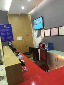 une salle d'attente avec un comptoir rouge et une télévision dans l'établissement Thank Inn Chain Hotel Zhejiang Hangzhou West Lake District, Sandun County, Oulubao Plaza, à Libu