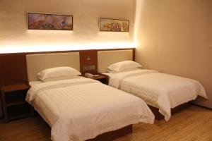 two beds in a hotel room with white sheets at Thank Inn Plus Hotel Fengxian Xidu in Xidu