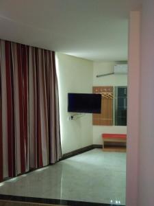 a living room with a television and a curtain at Thank Inn Chain Shangdong Zaozhuang Tengjingzhou Jinghe Bridge Haishang Mingyue in Tengzhou