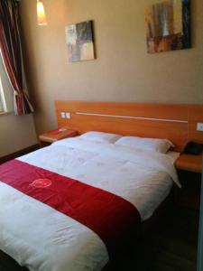 um quarto com uma cama com um cobertor vermelho e branco em Thank Inn Chain Hotel Shanxi Lvliang Jiaokou County West Street em Xiazhuang