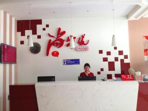 a woman is sitting at a counter in a office at Thank Inn Chain Hotel Shanxi Shangluo Shanyang Nanxin Street in Shanyang