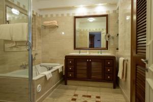 a bathroom with a tub and a sink and a mirror at Columbia Beach Resort in Pissouri