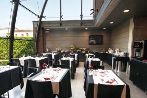 un ristorante con tavoli bianchi e sedie nere di Hotel Villa Giulietta a Fiesso dʼArtico