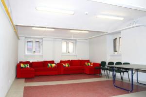 Una sala de estar con un sofá rojo y una mesa. en Szkolne Schronisko Młodzieżowe w Gdańsku, en Gdansk
