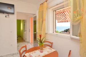 ein Esszimmer mit einem Tisch und einem Fenster in der Unterkunft Apartments Daniela in Zavalatica