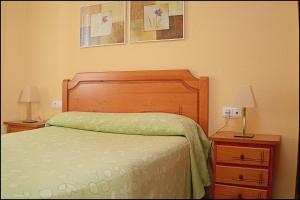 a bedroom with a bed and two night stands with lamps at Apartamento Cruz in Conil de la Frontera