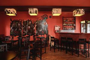a restaurant with a bar with chairs and a red wall at Fun House in Bucharest