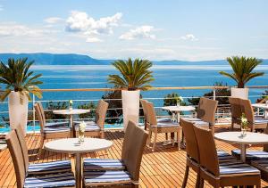 eine Terrasse mit Tischen und Stühlen und Meerblick in der Unterkunft Valamar Sanfior Hotel & Casa in Rabac