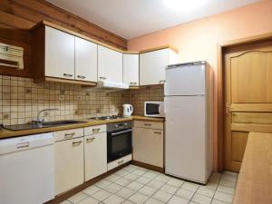 una cucina con armadietti bianchi e frigorifero bianco di Cosy Holiday Home in Noirefontaine with Garden a Bellevaux