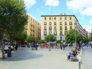 un grupo de personas sentadas en bancos en una calle de la ciudad en Moderno Apartamento en Lavapiés, en Madrid