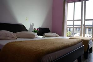 2 camas en una habitación con ventana en Hotel Manayara, en Campo Largo