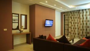a living room with a couch and a tv on a wall at Hotel Les Palmiers in Monastir