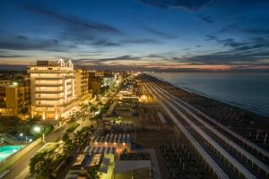 a view of a city at night with the ocean at Hotel Tiffany's in Riccione