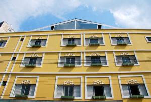 a yellow building with white windows andigil at Hotel Oriente in Itajubá