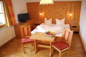 una camera con letto e tavolo con cesto di frutta di Hotel Garni Apart Elfriede a Fiss