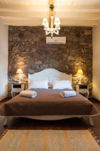 um quarto com uma cama grande e uma parede de pedra em Anemos Houses em Skala