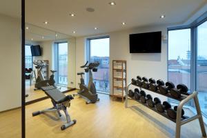 einen Fitnessraum mit Laufbändern und einem Flachbild-TV in der Unterkunft Eurostars Grand Central in München