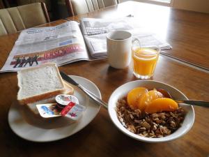 uma mesa com um prato de comida para o pequeno-almoço e um jornal em Princes Lodge Motel em Adelaide