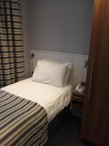 a bedroom with a bed with a white pillow and a phone at Carlton Hotel in Ilfracombe