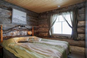 a bedroom with a bed in a room with wooden walls at Sielikkö Aurora Log Villas in Saariselka