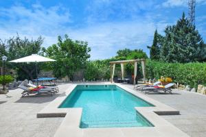 a swimming pool with two chairs and an umbrella at Owl Booking Villa Gabelli - Rustic Stay with Great Views in Campanet